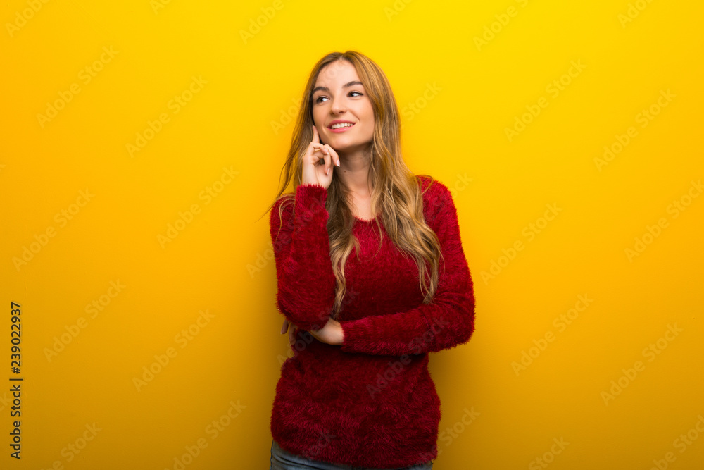 Young girl on vibrant yellow background thinking an idea while looking up Young girl on vibrant yellow background thinking an idea while looking up