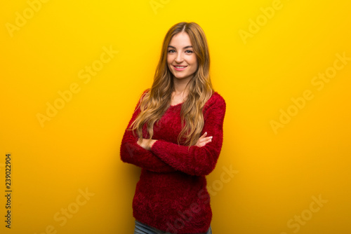 Young girl on vibrant yellow background keeping the arms crossed in frontal position