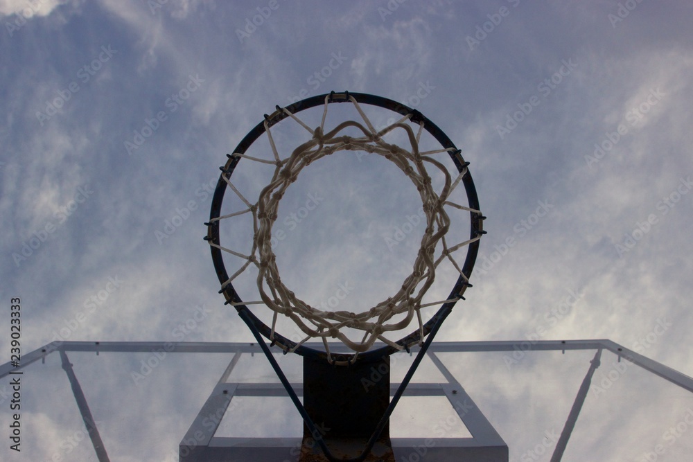 Look at the blue cloudy sky trough a basketball ring with net and transparent glass board Look at the blue cloudy sky trough a basketball ring with net and transparent glass board