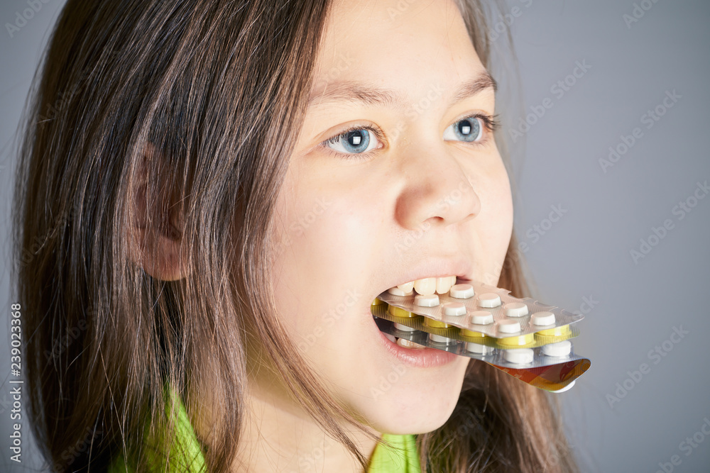 Cute girl with beautiful eyes holds in her teeth pack of pills from the disease. Cute girl with beautiful eyes holds in her teeth pack of pills from the disease.