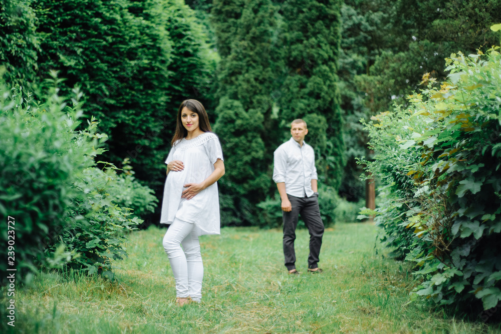 Fototapeta premium Happy and young pregnant couple hugging in nature