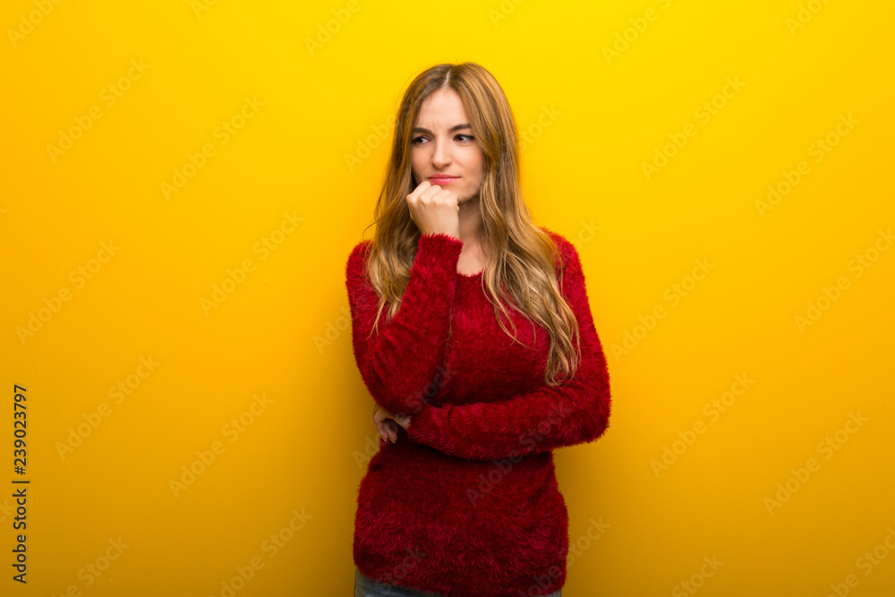 Young girl on vibrant yellow background having doubts Young girl on vibrant yellow background having doubts