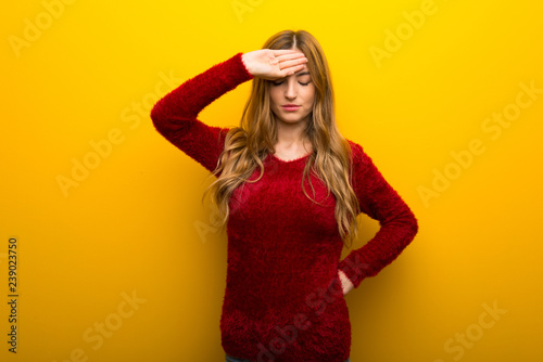 Young girl on vibrant yellow background with tired and sick expression