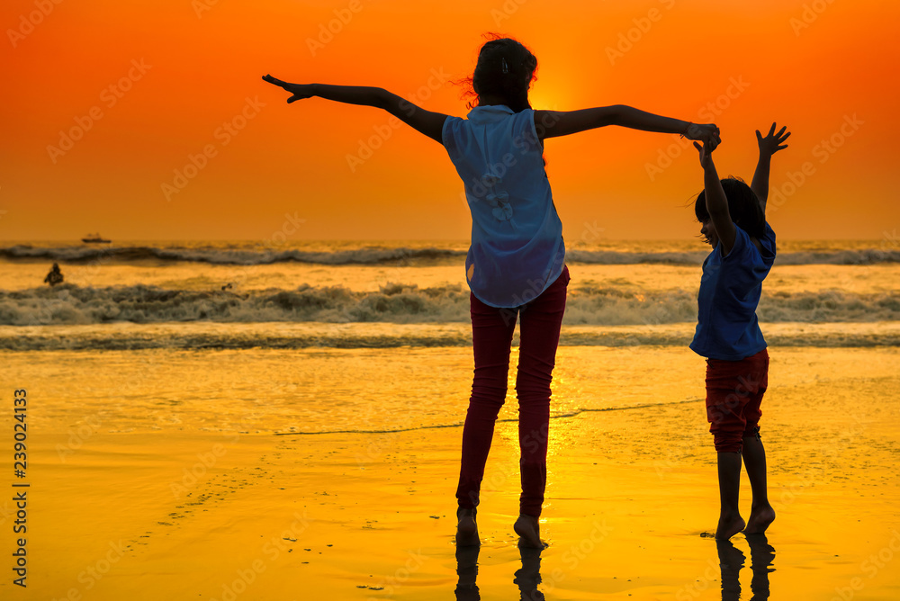 Fototapeta premium Two happy young girls dancing at the beach on sunset. Beach holidays travel concept. 