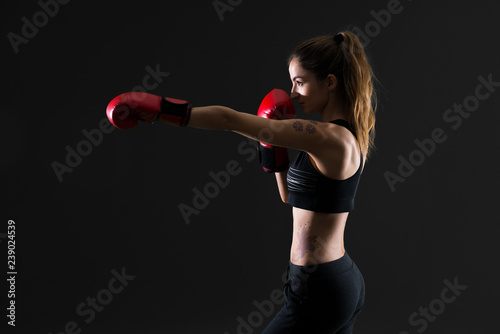 Sport woman with boxing gloves on dark background