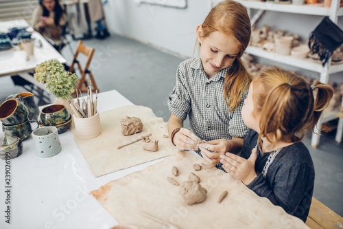 two awesome girls in the sculpture studio learning to work with clay. close up sidee view shot.copy space photo