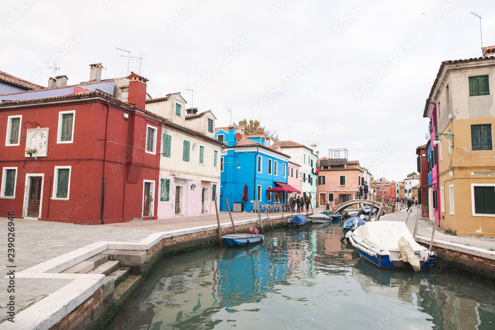 Tourism in Venice, Burano Island, colored architecture, canal and boats. Trip to the island of Venice.