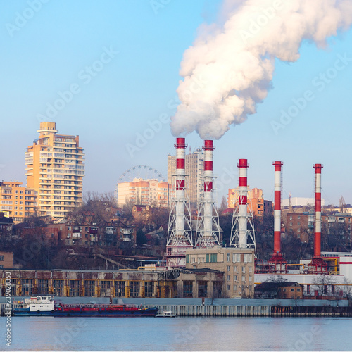 The plant emits pollutants into the atmosphere  from the factory pipes comes out a thick smoke.the pipes emit steam on the background of the city