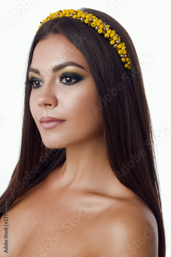 Portrait of beautiful brunette woman with big earring and shinny yellow accessories in hair. Perfect arabic makeup with long hair. Looking and turned away. Isolate shot on white background. Side view photo