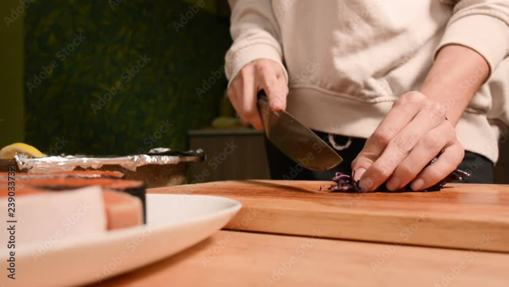 Closeup of the hands of a girl at the home kitchen on a wooden cutting board small cherry tomatoes. Home cooking Closeup of the hands of a girl at the home kitchen on a wooden cutting board small cherry tomatoes. Home cooking