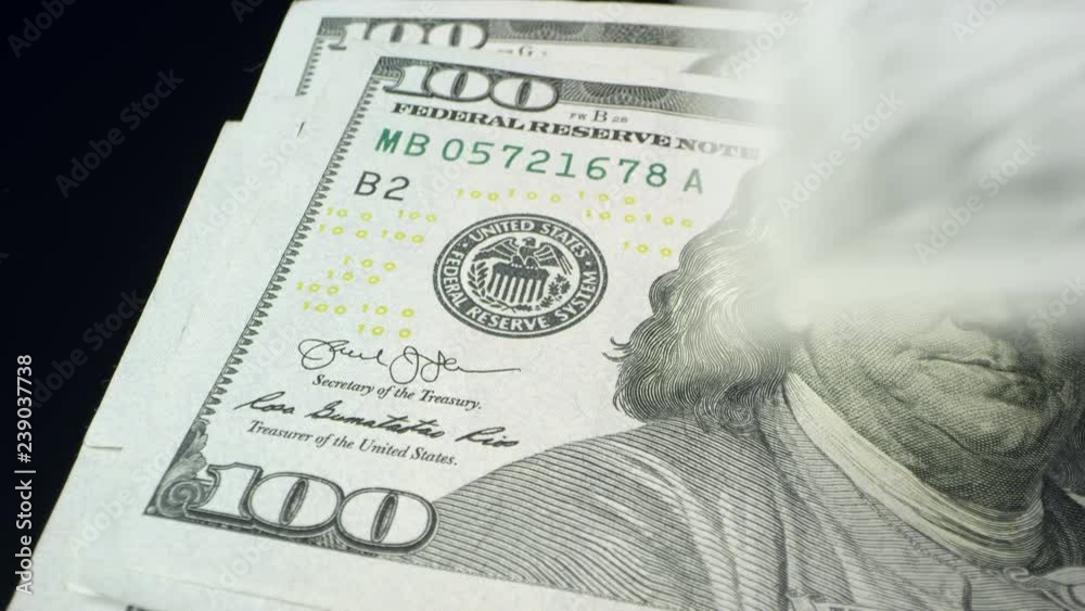 Up close view 100 dollar bills left side being counted as they are placed one by one on each other.