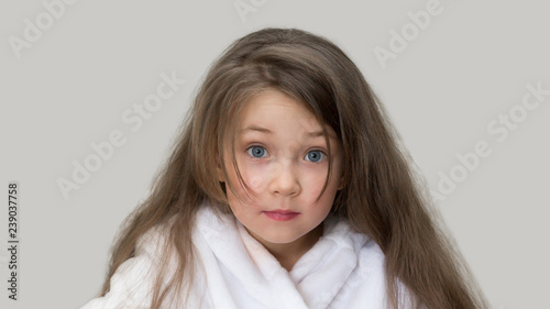 Surprised girl in a white coat. Girl 4-5 years old with long flowing hair in a white bathrobe after a bath. photo