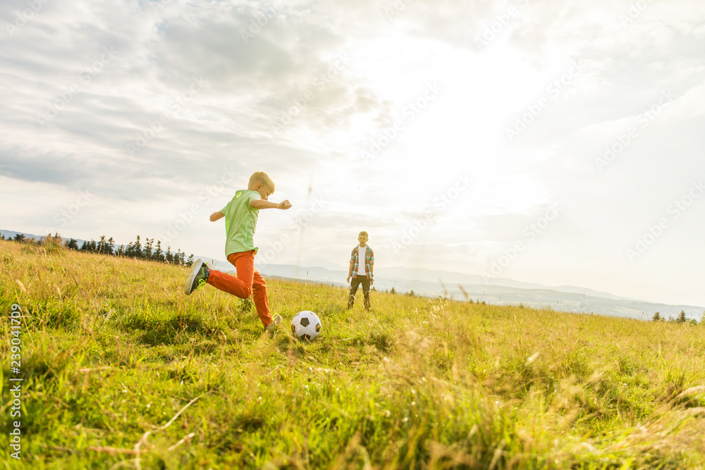 Boys playing football in a meadow, having fun