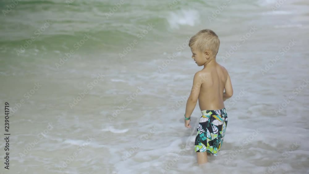 Cute little boy in a bathing suit playing with bucket on the beach 4k Cute little boy in a bathing suit playing with bucket on the beach 4k