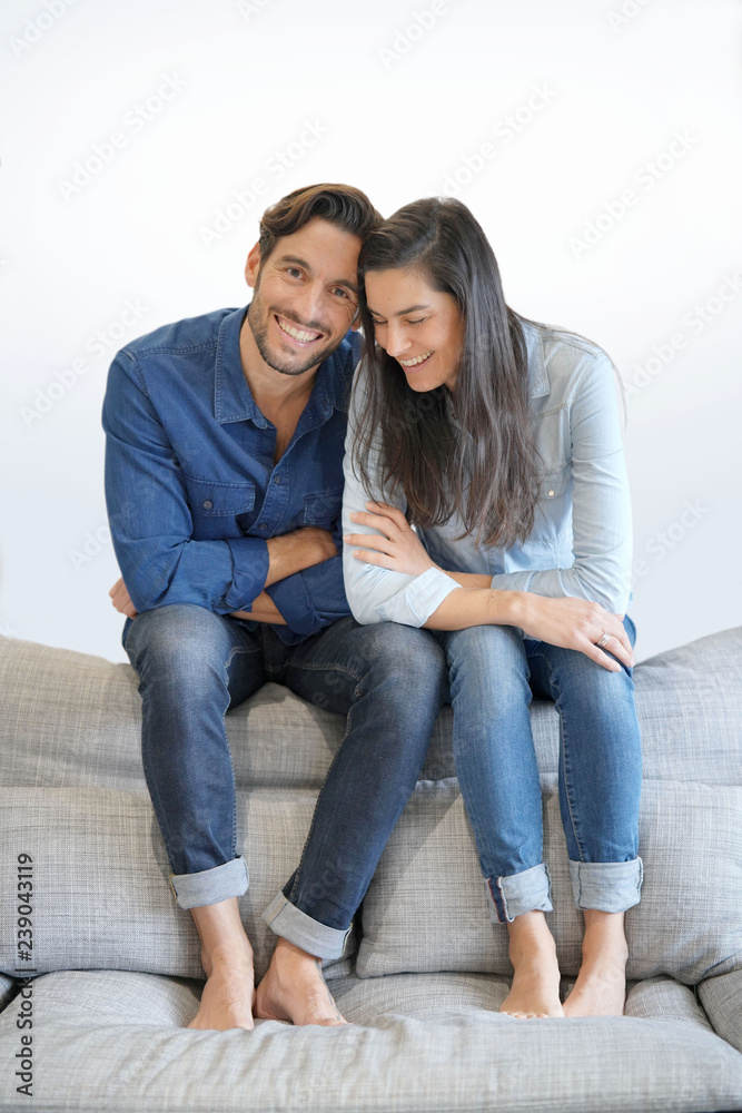 Isolated gorgeous smiling couple in denim on comfy couch