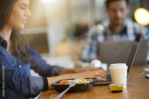 Foto Beautiful woman eating lunch whilst working in co working space