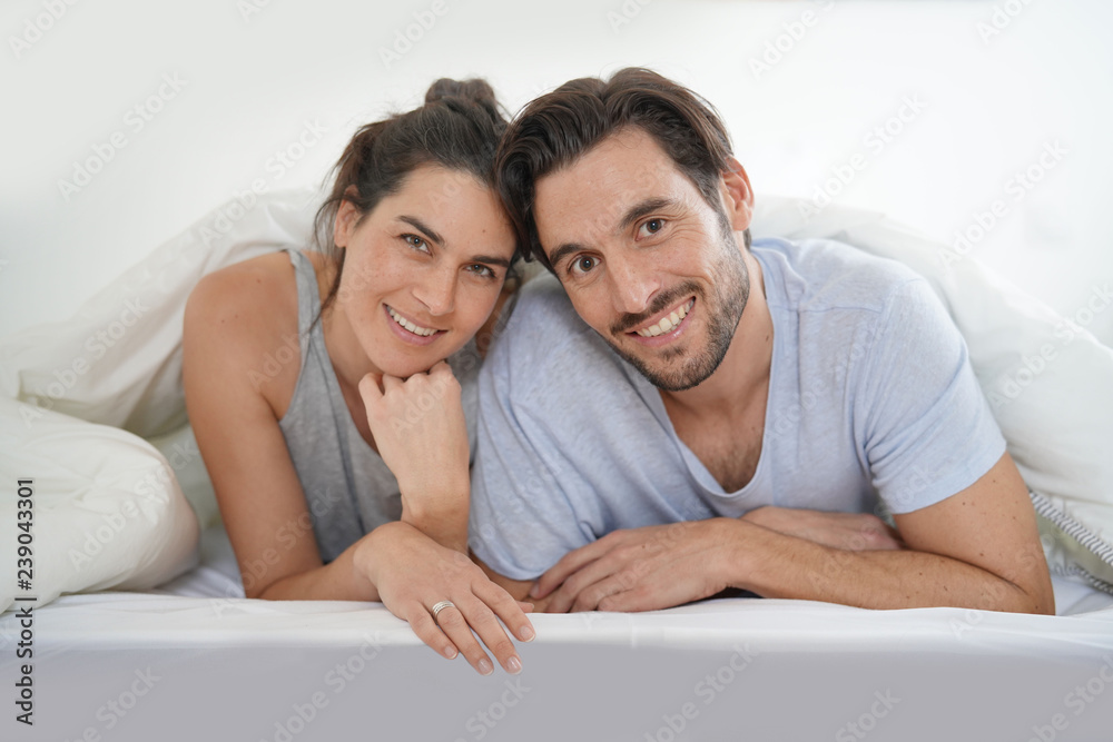 Isolated stunning couple looking at camera smiling in bed Isolated stunning couple looking at camera smiling in bed