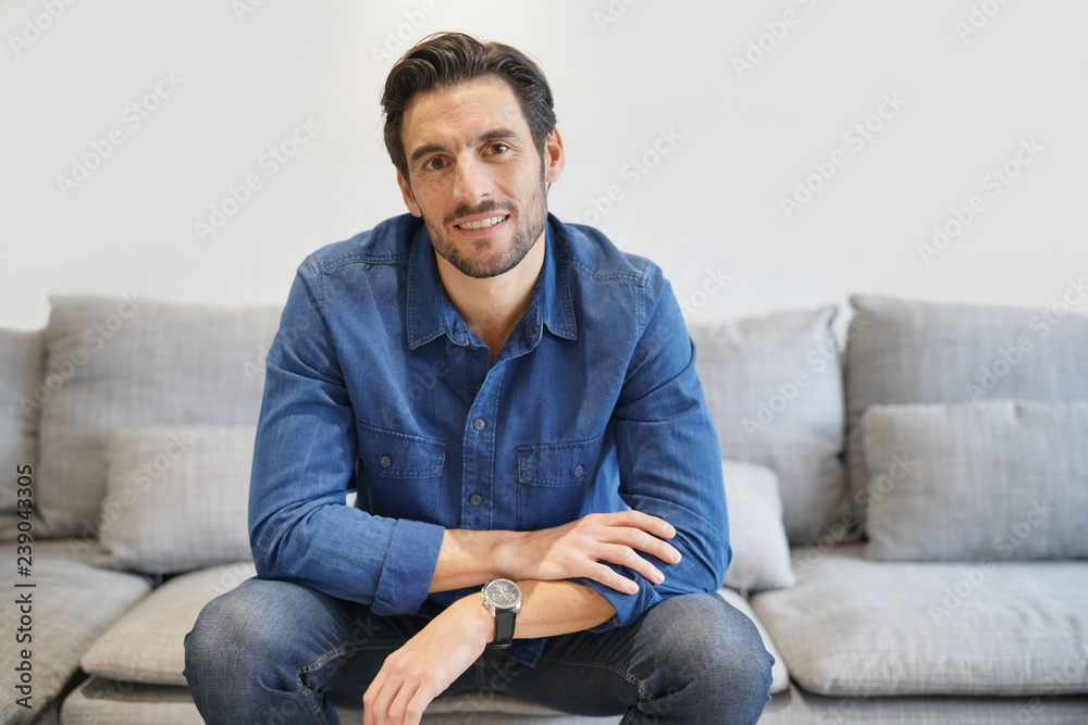 Isolated handsome man in denim on comfortable couch Isolated handsome man in denim on comfortable couch