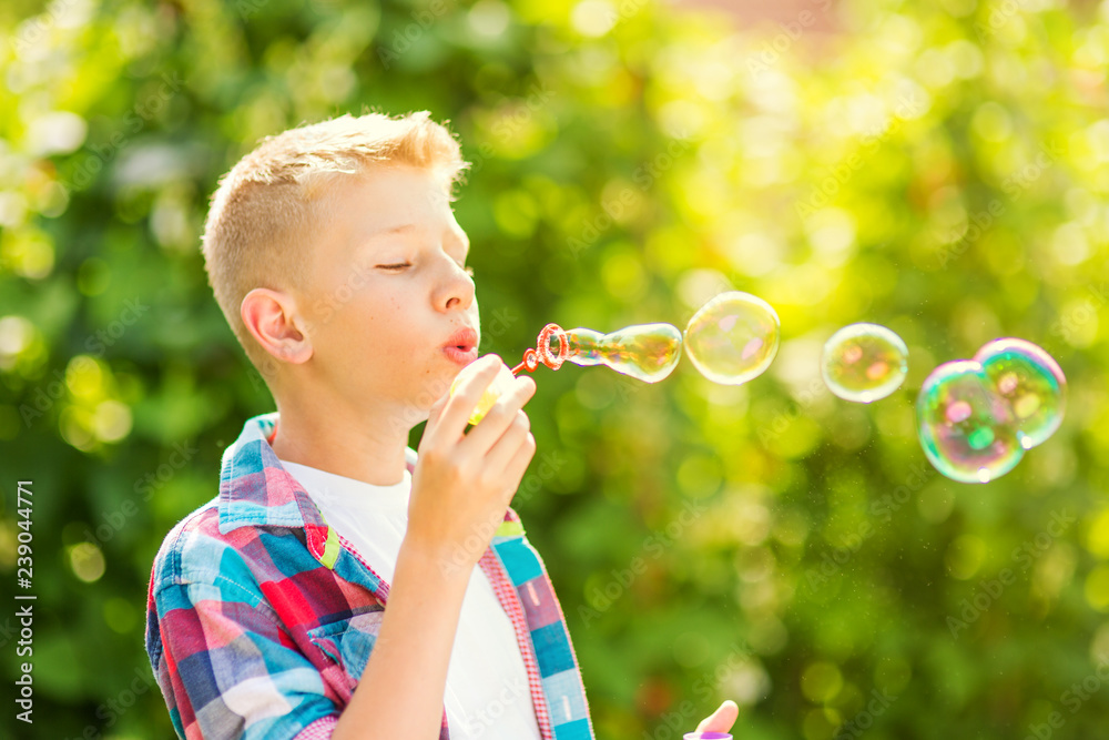 Portrait of a young boy blowing soap bubbles in a park Portrait of a young boy blowing soap bubbles in a park