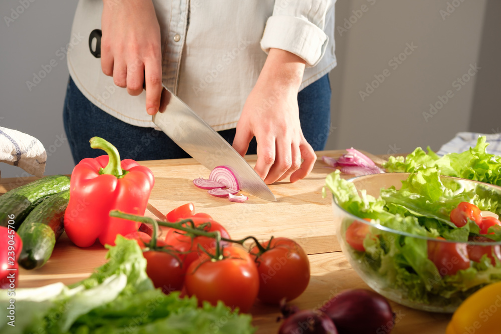Girl cuts red onions for vegetable salad. Cooking salad