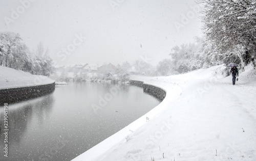 Winter scene - snowing, river, white cityscape