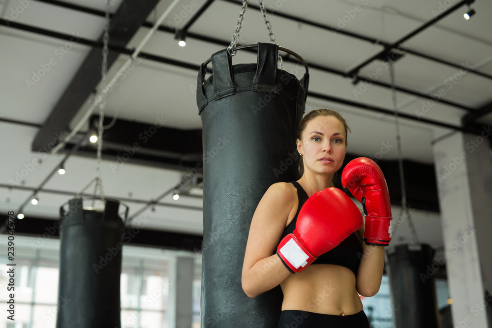 beautiful young girl in boxing gloves near the punching bag in the gym in training
