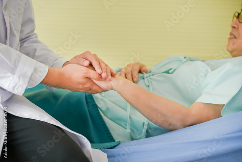 Asian male doctor, hold hands of patients An elderly woman, to comfort and encourage to receive treatment. to healthy and health insurance concept.