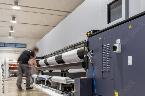 Big paper feed during Computer aided printing process, advanced technology in the press and publishing sector, latest generation robotized plotting machines for mass production and big format prints.
