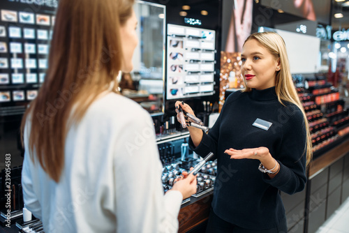 Seller shows to client eyeshadows in make-up shop