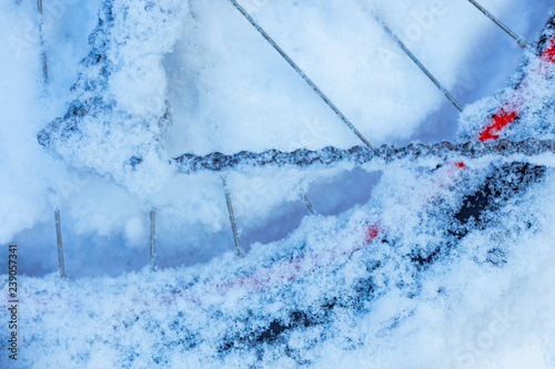 closeup of bicycle wheel with spokes, chain and transmission parts lying in snow partly covered. selective focus, shallow depth of field, all weather winter cycling, extreme outdoor © shanshinyury