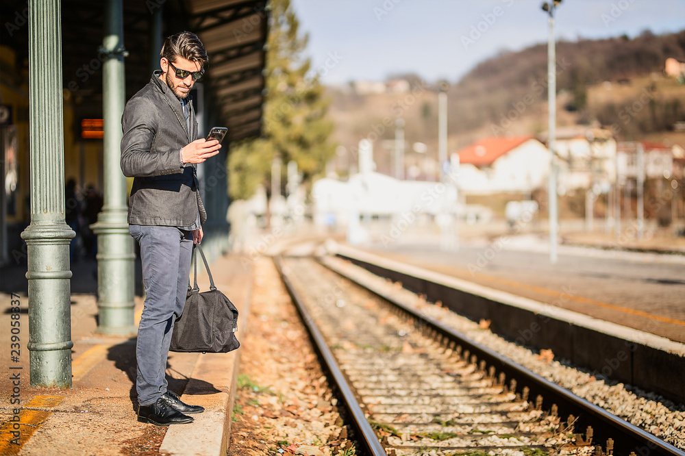 Young traveler man holding smartphone while waiting for train