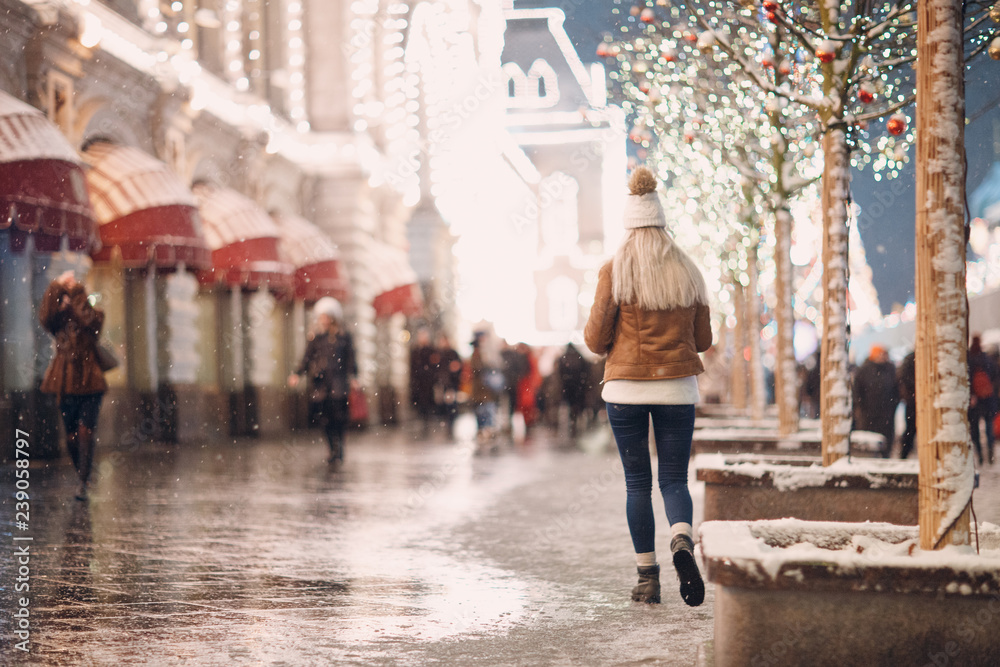 Young woman walking on the winter street city. Back view.