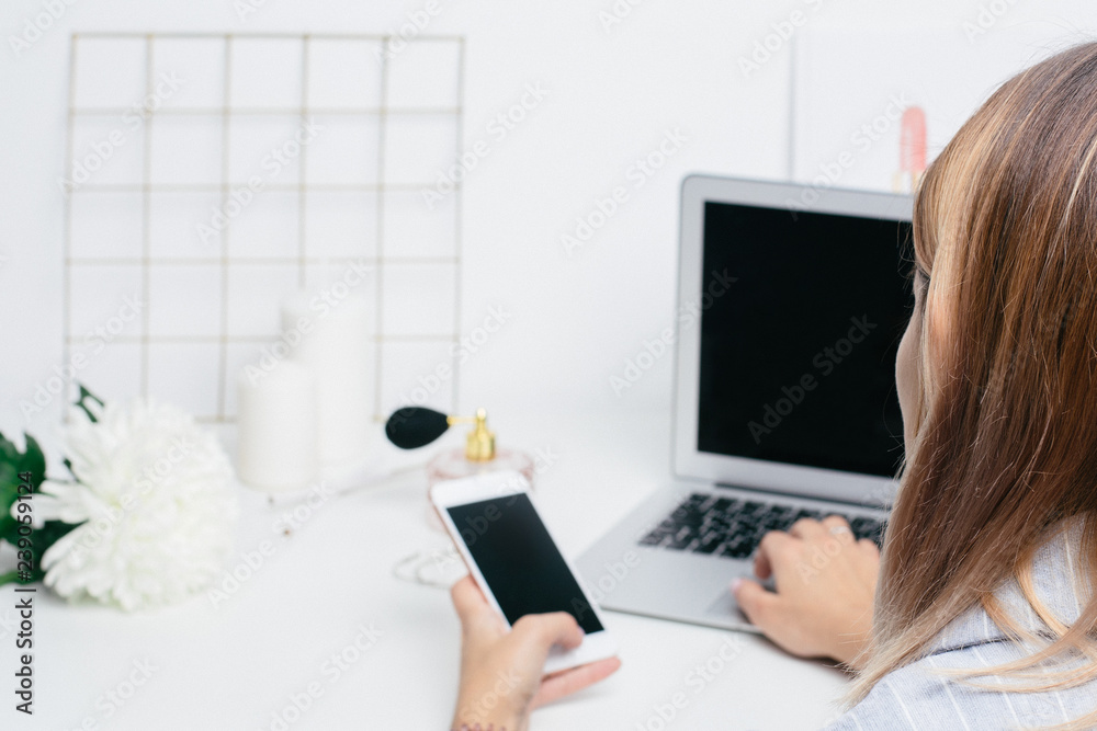 Girl hold blank screen phone and laptop keyboard on white office table Girl hold blank screen phone and laptop keyboard on white office table