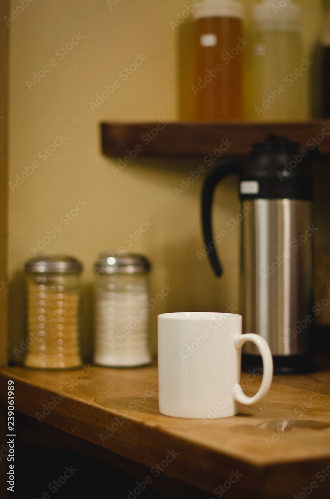 A long view of the solo white mug on the sugar station of the cafe. A long view of the solo white mug on the sugar station of the cafe.