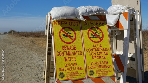 Tablou pe pânză Signs  warn of sewage contaminated water near border