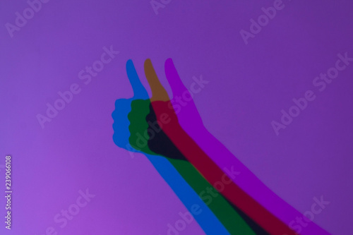 sombra de mano con pulgar hacia arriba desplegado en tres colores sobre fondo morado photo
