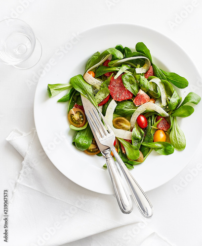 salad dish with tomatoes lattuce chestnuts on a white table