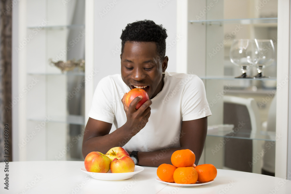 African man eating apple in kitchen