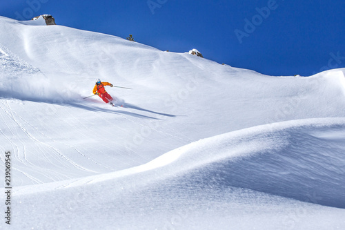 freeride skier skiing downhill through deep powder snow