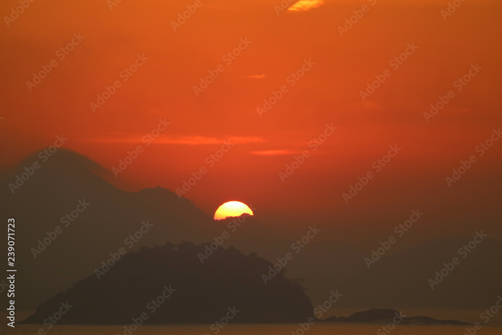 Sun rising from the cloud layer over Atlantic ocean view from Copacabana beach in Rio de Janeiro of Brazil