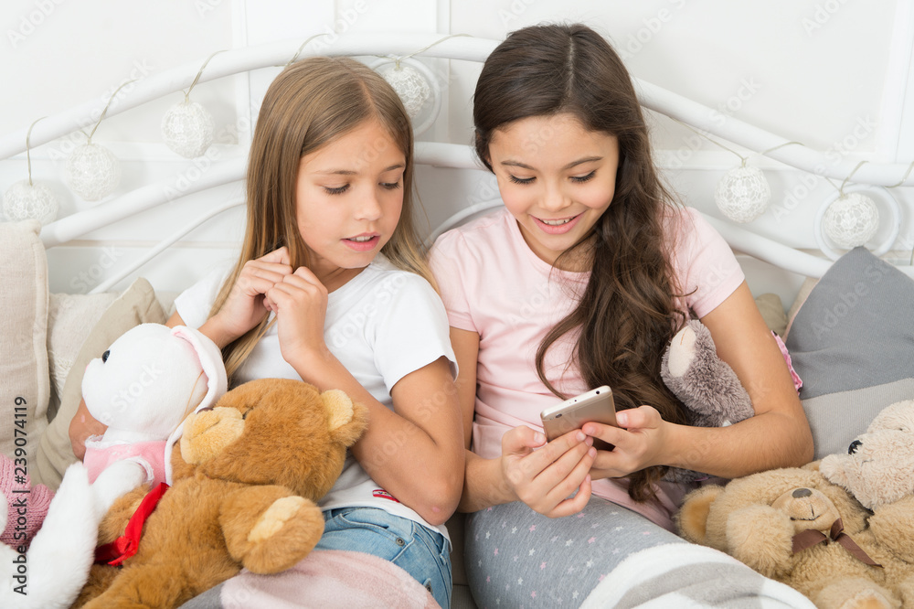 Texting to Santa. Happy little children with mobile phone. Little girls use smartphone in bed. Ordering gifts for Christmas and New Year by phone. Merry Christmas and Happy New Year greetings Texting to Santa. Happy little children with mobile phone. Little girls use smartphone in bed. Ordering gifts for Christmas and New Year by phone. Merry Christmas and Happy New Year greetings