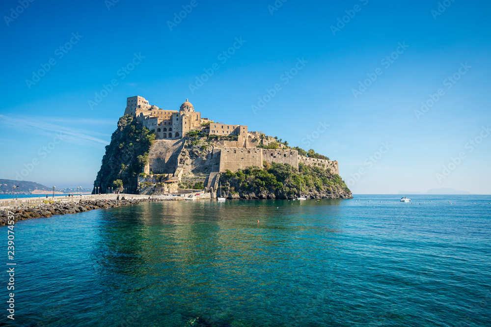 Scenic morning view of the dramatic stone fortress of Aragonese Castle looming from its ancient mountaintop perch above the Mediterranean island of Ischia, Italy