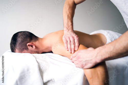 Physical Therapist Massaging Arm Of The Young Man