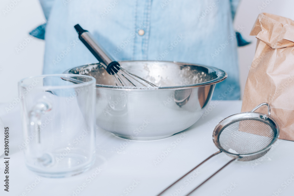 Close-up white kitchen table with utensils and metal bowl Close-up white kitchen table with utensils and metal bowl