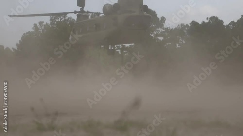 Slow motion view of a military convertiplane taking off from a forest photo