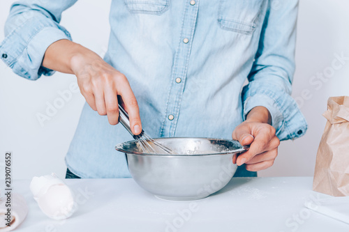 Woman whisking dough in metal bowl