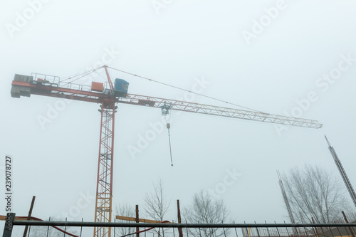 Construction crane in fog early morning - urban view