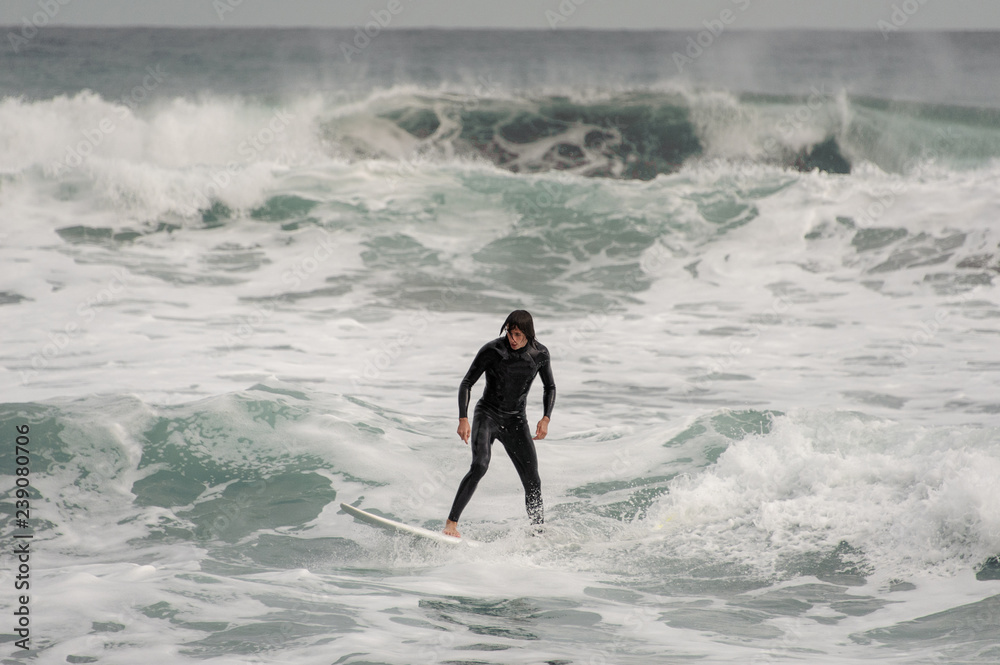 Brunette guy in the swimsuit professionally riding on a surf on the sea Brunette guy in the swimsuit professionally riding on a surf on the sea