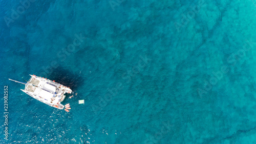 Top view of catamaran against clear turquoise sea waters .