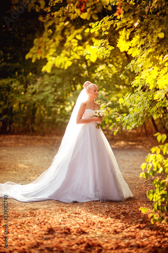 Beautiful bride in white dress in the autumn garden